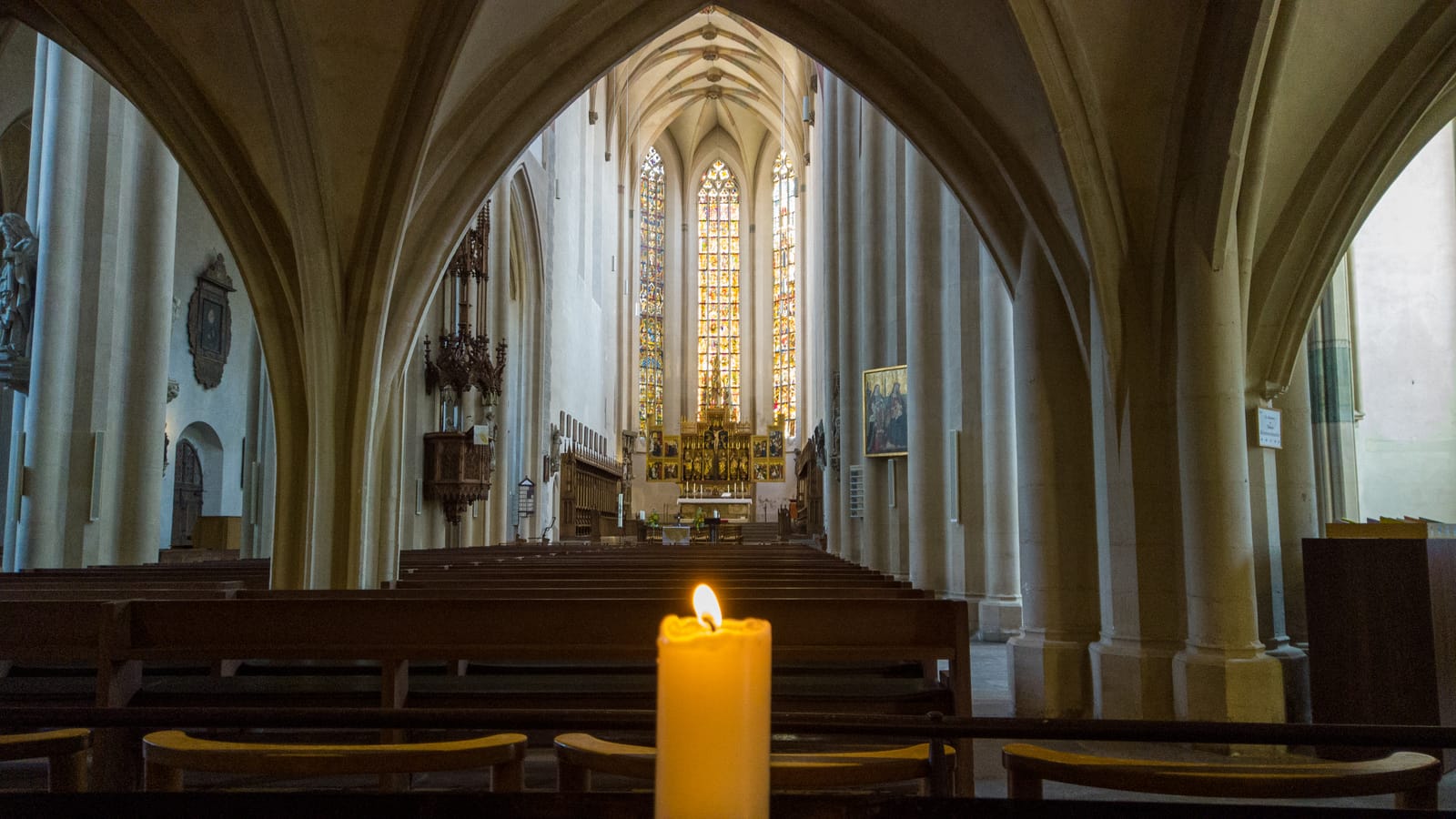 A single candle burning in the quiet, vaulted interior of a village church