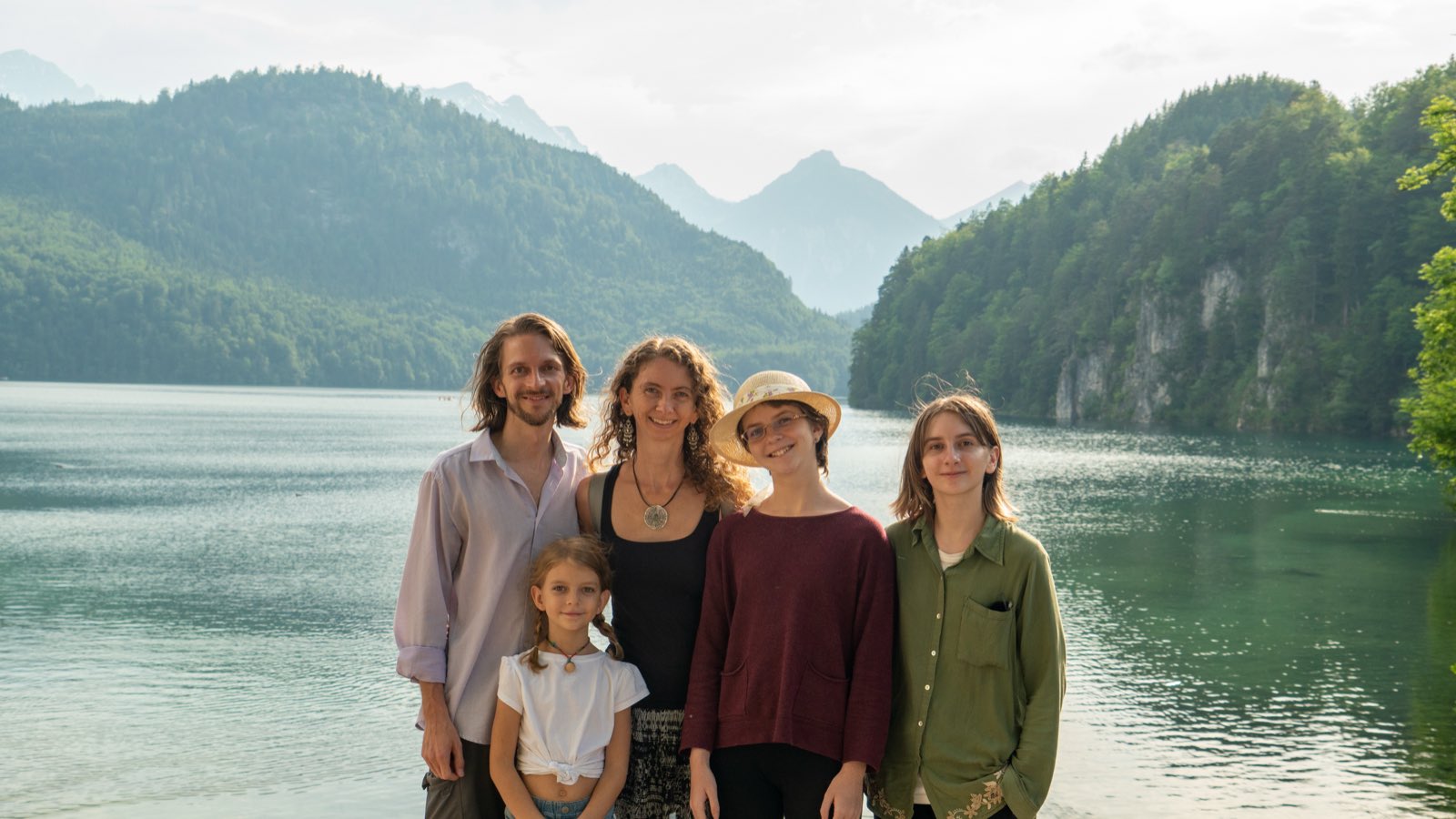 The five of us in front of the still, green Alpsee, with hazy mountains rising behind