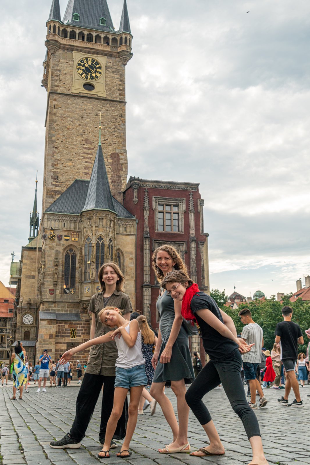 Jennifer and the three girls striking a playful pose on the cobblestones below Prague's Old Town Hall clock tower