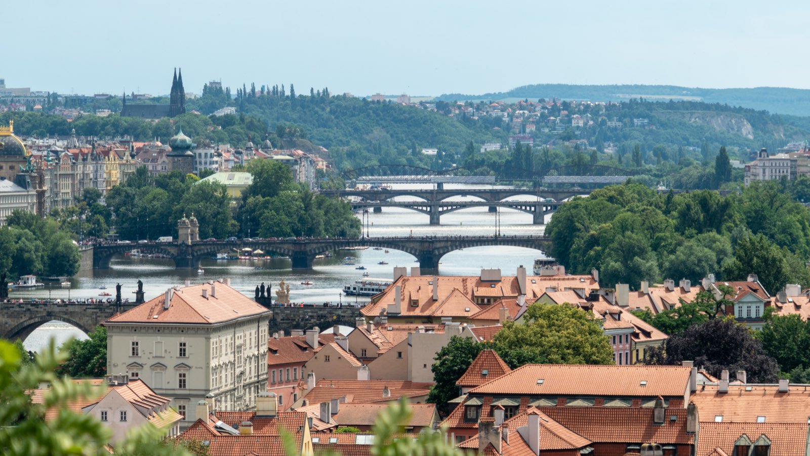 A layered view of the Vltava's many bridges lined up across the river, red-tiled rooftops in the foreground